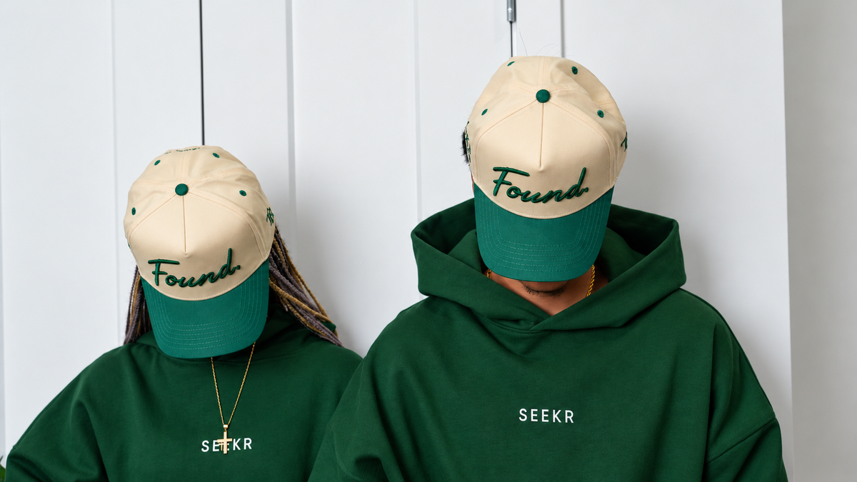 Two models wearing the Found Cap in green with SEEKR hoodies, Found script clearly visible