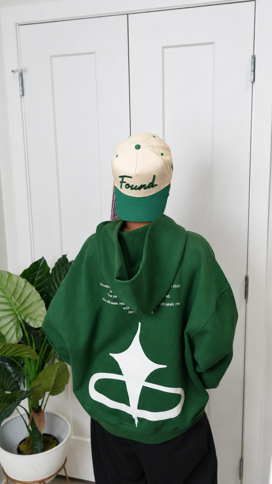Back view of a model in the Found Cap in green with a green SEEKR hoodie